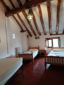 a room with three beds and a ceiling with beams at Casa de pelegrinos la perlanegra 