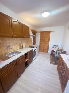 Una cocina con gabinetes de madera y un fregadero y una mesa. en Apartmán v Trutnově, en Trutnov