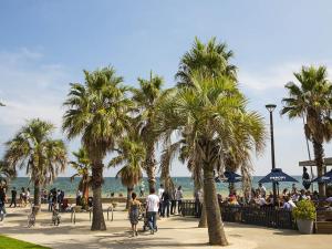 people walking on a sidewalk near the beach with palm trees at Entire Studio Apartment in St Kilda FREE PARKING WIFI BEACH WALK in Melbourne