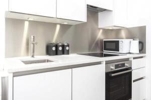 Una cocina blanca con fregadero y microondas. en River & Hospital Base, Kings Road Retreat, en Reading 6 fotos más