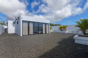 a white house with large windows on a gravel yard at Rocky 39 in Grand-Baie