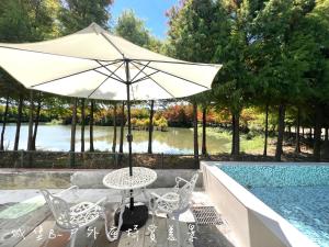 Una mesa y sillas con una sombrilla junto a una piscina. en 夢幻城堡民宿, en Wujie 12 fotos más