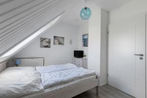 - une chambre blanche avec un lit et un escalier dans l'établissement Fewo Küstkieker, à Sankt Peter-Ording