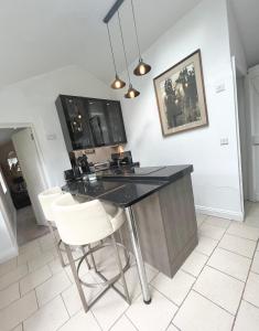 une cuisine avec un comptoir noir et des chaises blanches dans l'établissement Storeybook cottage, à Oswestry