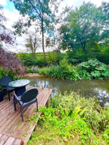 une table et des chaises sur une terrasse en bois à côté d'une rivière dans l'établissement Storeybook cottage, à Oswestry