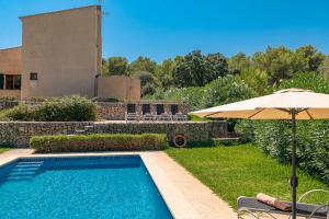 a pool with an umbrella next to a house at Villa Comellar by Sealand Villas in Artá