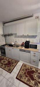 a kitchen with white cabinets and a sink and two rugs at Pensiunea Ela Novaci in Novaci