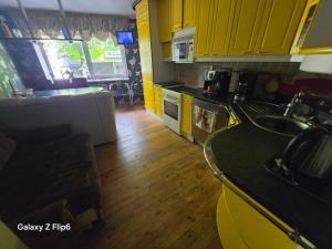 a kitchen with yellow cabinets and a wooden floor at Willa Ranna Resort in Pärnu