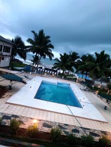 a large swimming pool with palm trees in the background at LLOYDS BEACH RESORT and SPA in Kokrobite