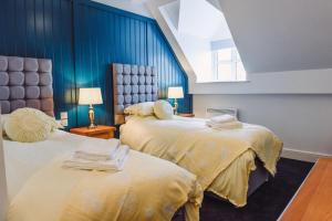 two beds in a room with blue walls at The Raven Pub with Rooms, Worcester in Worcester