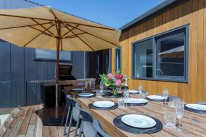 a wooden table with an umbrella on a deck at Prowess Lodge luxury accommodation with private pool and spa in Wanaka