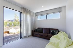 a living room with a couch and a sliding glass door at Prowess Lodge luxury accommodation with private pool and spa in Wanaka +40 photos