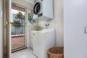 cocina pequeña con lavadora y ventana en The Shack on Caffrey - Port Willunga, en Port Willunga