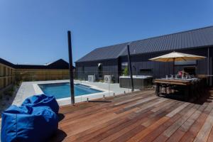 a deck with a table and an umbrella next to a pool at Prowess Lodge luxury accommodation with private pool and spa in Wanaka