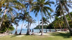 a group of people standing on a beach with palm trees at Bateau MEKKALA in Ban Bang Bao