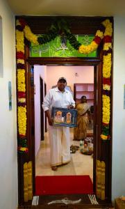 a man standing in a doorway holding a box at New RPM Home Stay Gubera Nagar in Tiruvannāmalai