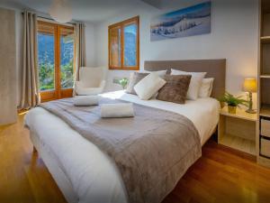 Un dormitorio con una cama grande y una silla. en Chalet Aravista - OVO Network, en Le Grand-Bornand