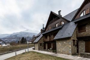 un vieux bâtiment avec une montagne en arrière-plan dans l'établissement Casa Rústica - Sorieus Lodge en Lérida, à Bossost