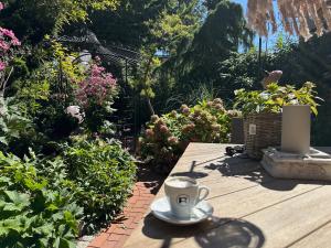 a cup of coffee sitting on a wooden table in a garden at RitterLiving Ferienapartment am Markt in Tangermünde +34 photos