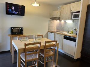 cocina con mesa con sillas y TV en la pared en Loc luz st sauveur 6, en Luz-Saint-Sauveur