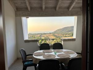 タナウネッラにあるAlba Vista Mare - Apartment mit Meerblick und Pool Budoni, Sardinienの大きな窓のある部屋にあるテーブルと椅子