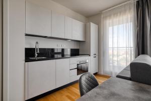 a kitchen with white cabinets and a table with chairs at GiaxTower Gym Spa & Pool Skyline View 20' piano in Milan