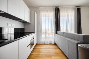 a kitchen with white cabinets and a gray couch at GiaxTower Gym Spa & Pool Skyline View 20' piano in Milan +26 photos