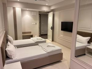 a hotel room with two beds and a mirror at Swarn Hotel in Kolkata