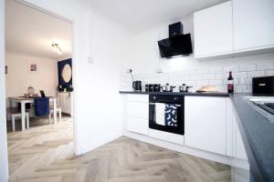 eine Küche mit weißen Schränken und einem schwarzen Herd in der Unterkunft Home with Ocean View - Contractors and Families in Port Talbot