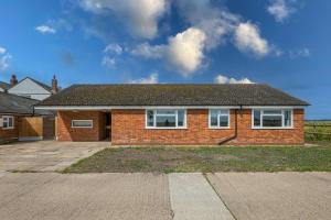 a brick house with white windows on a driveway at Grapnells Lodge, Wallasea Island, Rochford, Essex in Rochford