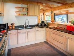 a large kitchen with wooden cabinets and a sink at Chalet Musini - OVO Network in Le Grand-Bornand +18 photos