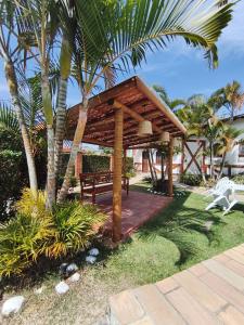 a wooden pavilion with a bench and a palm tree at Hotel Villar in Penedo