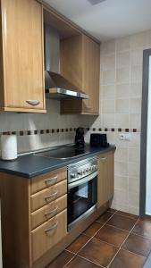 a kitchen with wooden cabinets and a stove top oven at Luminoso 3 Rooms Vistas Pirineo in Sabiñánigo