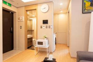 a living room with a tv and a clock on the wall at Haeundae Lamer Stay in Busan +291 photos