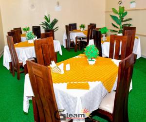 a dining room with tables and chairs with green carpet at The Gleam Hotel in Mai Mahoro