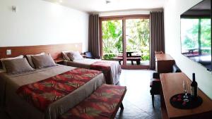 a hotel room with two beds and a balcony at Araticum Praia Hotel in Santo André +29 photos