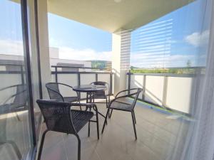 balcón con 4 sillas, mesa y ventana en VIA Apartmany, en Trenčín