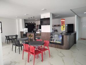 a restaurant with tables and red chairs and a counter at Golden Dolphin Supreme in Caldas Novas