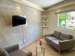 a living room with a couch and a television on a wall at Studios Don Bosco in Santo Domingo