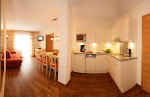 a kitchen and living room with white cabinets and a table at Apart Garni Hax'n Tenne in Serfaus