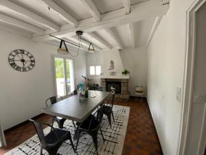 Un comedor con una mesa y sillas y un reloj. en Maison Saint Marc sur Mer, en Saint-Nazaire