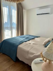 a bedroom with a bed with a blue blanket and a window at Гнездото l The Nest in Burgas City