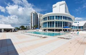 a pool in front of a building with lounge chairs at UNIT #908 Castle Beach Club Condominium in Miami Beach