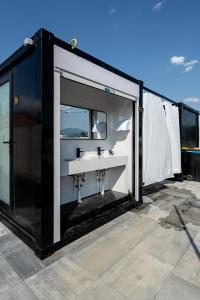 Un edificio en blanco y negro con un lavabo y un espejo. en Schitterhof CAMPING WEISS, en Spielberg