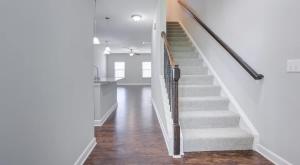 eine Treppe in einem Haus mit weißen Wänden und Holzböden in der Unterkunft Upscale King 3BR Townhouse Pineville in Charlotte