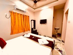 Habitación de hotel con cama y cortina amarilla en Nikilan Residency, en Rameswaram