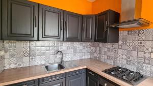a kitchen with black cabinets and a sink at Gîte La Malavisée in Leernes