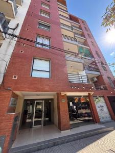 a tall red brick building with a store front at Departamento centrico Avenida Cordoba Edificio Campanarios XIX in Esperanza