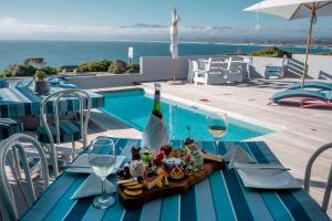 a table with a plate of food and wine glasses at 65onCliff - 4 Bedroom Home Selfcatering in De Kelders