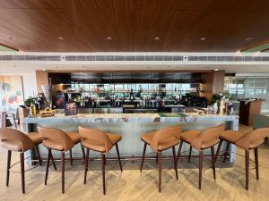 a bar in a restaurant with brown stools at Ramada Encore by Wyndham Gurugram Dwarka Expressway in Gurgaon